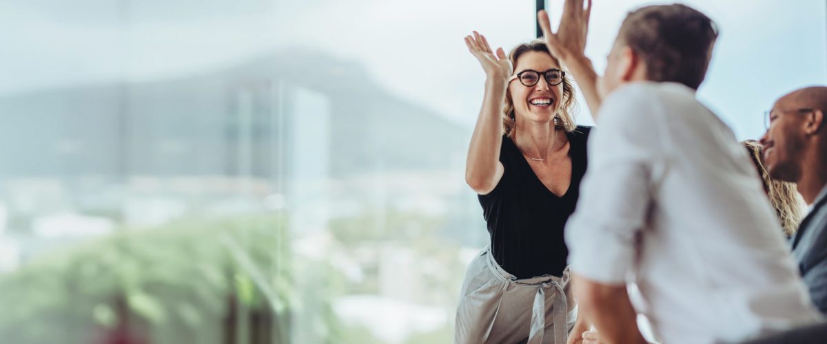 Businesswoman giving a high five to male colleague in meeting. Business professionals high five during a meeting in boardroom.
