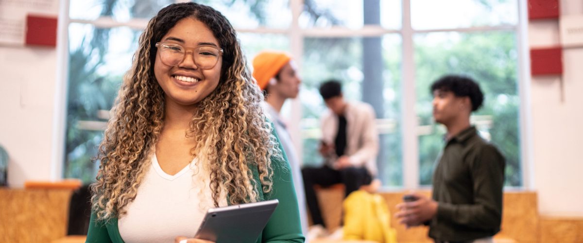 Portrait of a young student woman holding a digital tablet at university