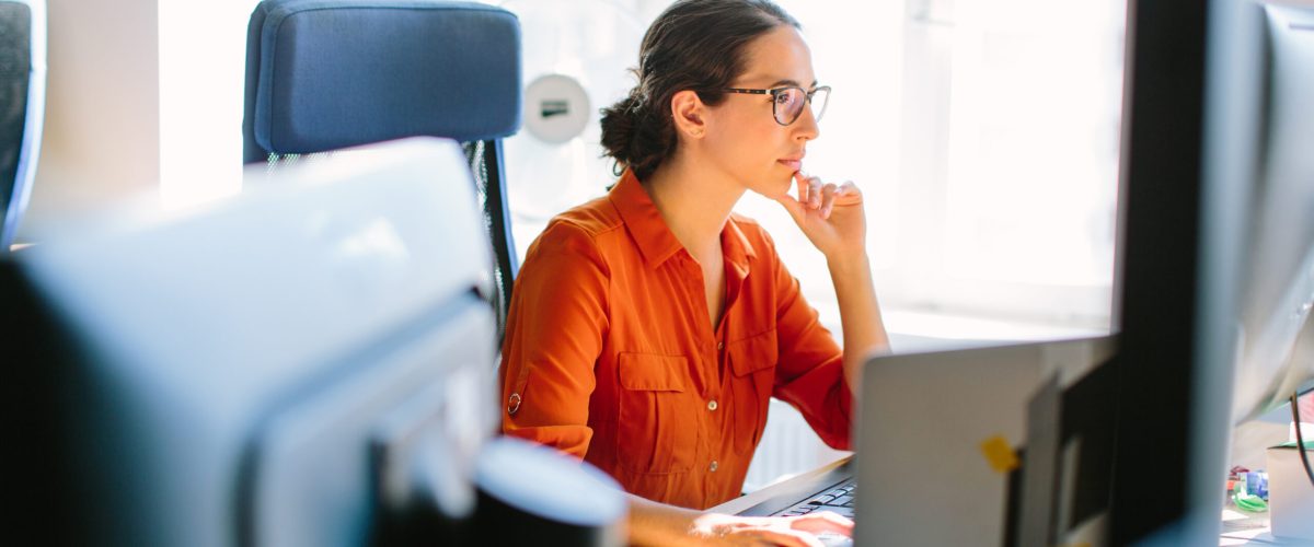 Shot of business woman sitting at her desk and working on desktop computer